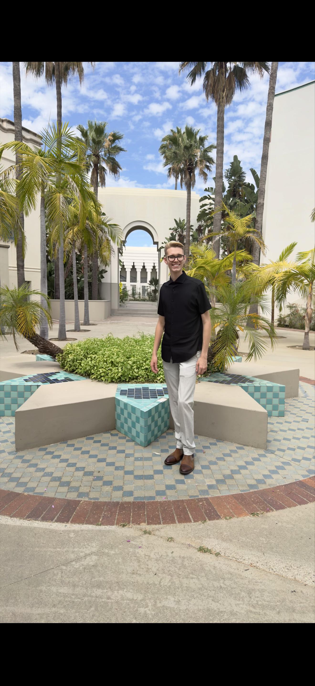 Full-length outdoor photo of Dakota in a black shirt, light trousers, and brown shoes