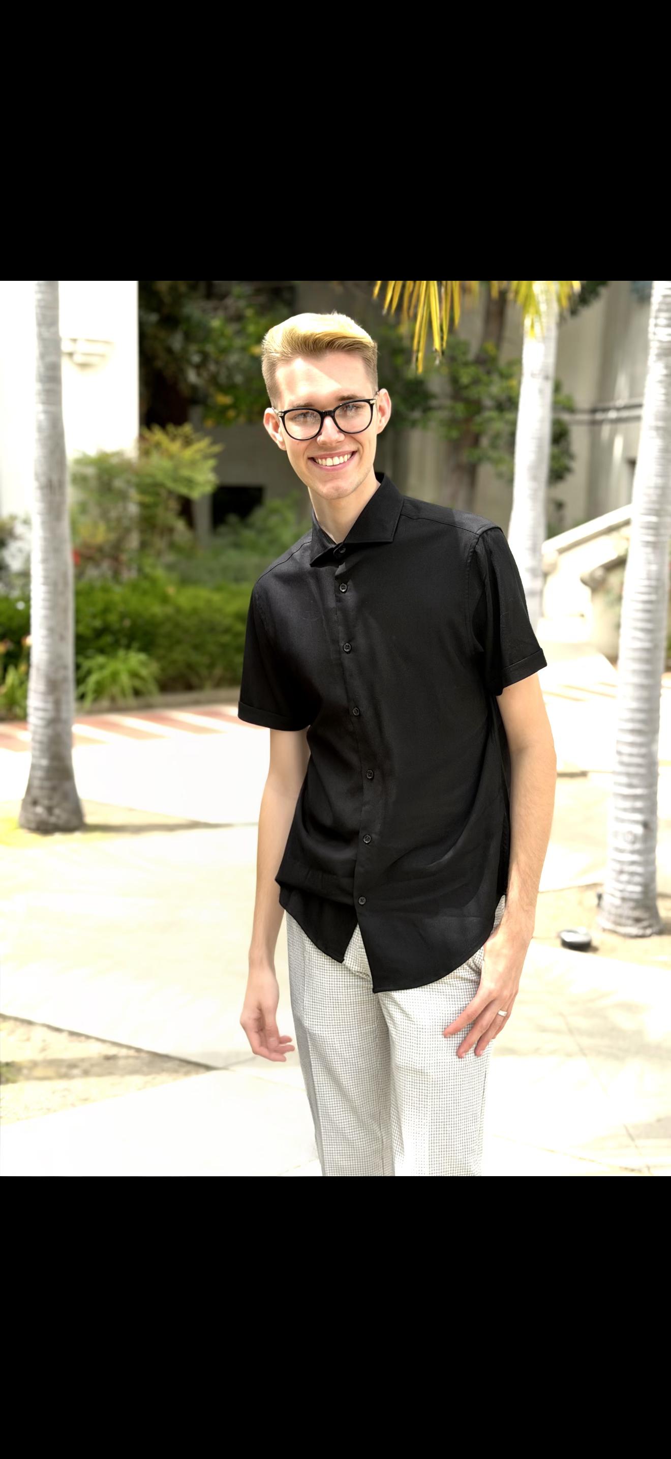Dakota smiling in glasses and a black shirt outdoors